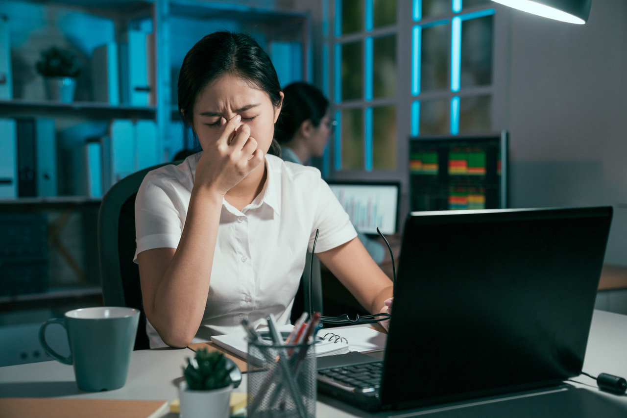 Junge Frau vor dem Laptop mit Kopfschmerzen und Migräne