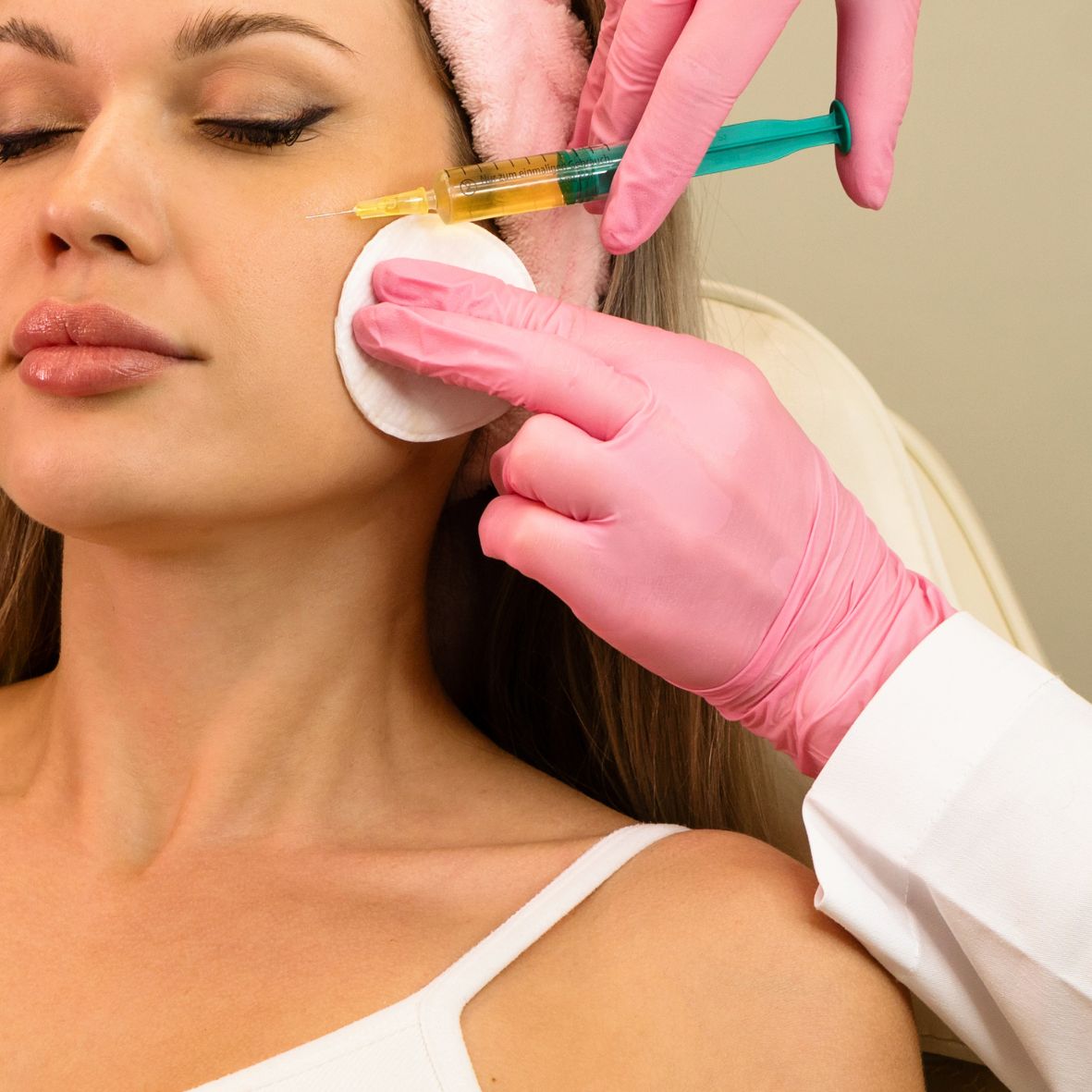 Ein weibliches Gesicht während einer Platelet Rich Plasma (PRP) Behandlung und ein Arzt der eine Spritze hält.
