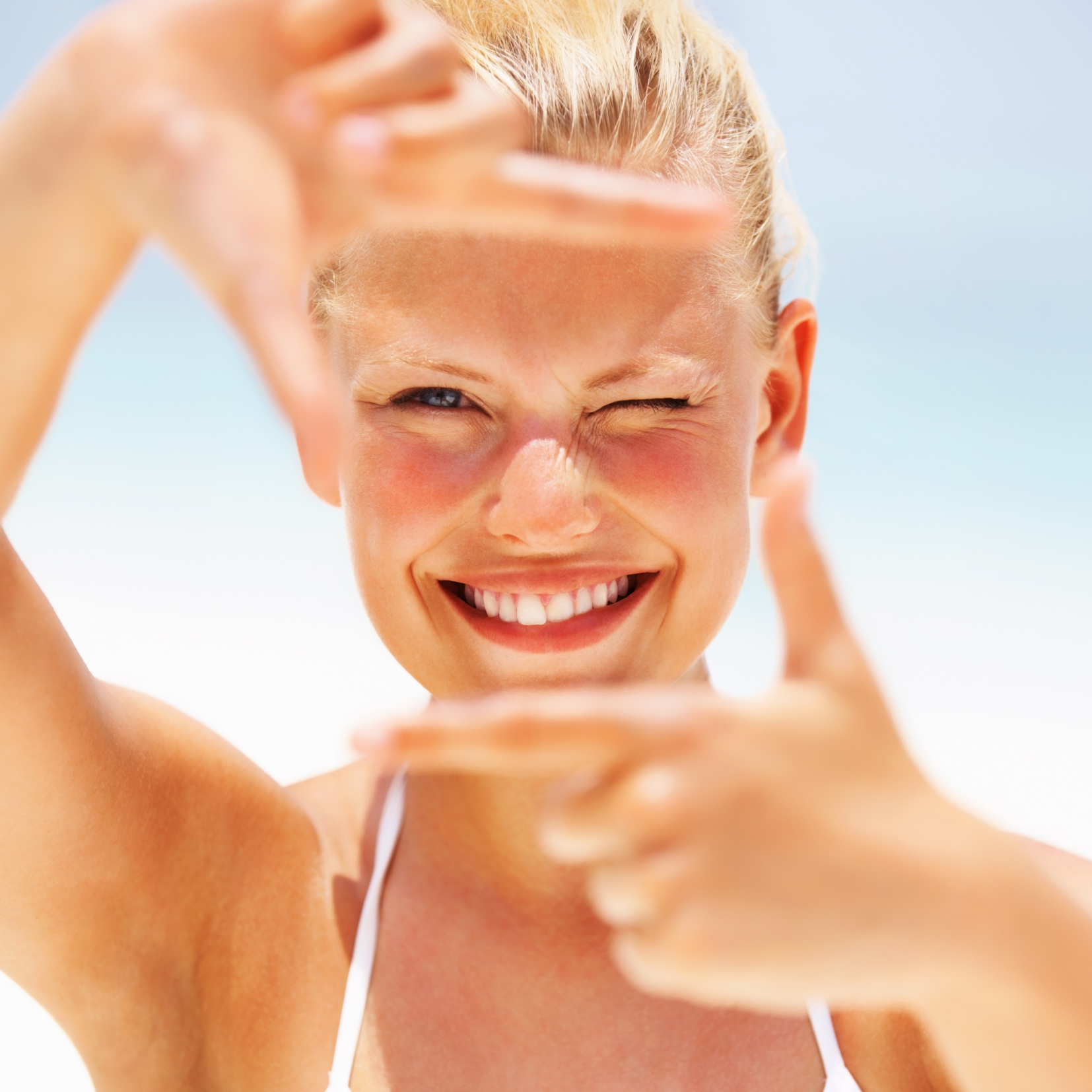 Frau am Strand, in der Sonne und sie lacht.