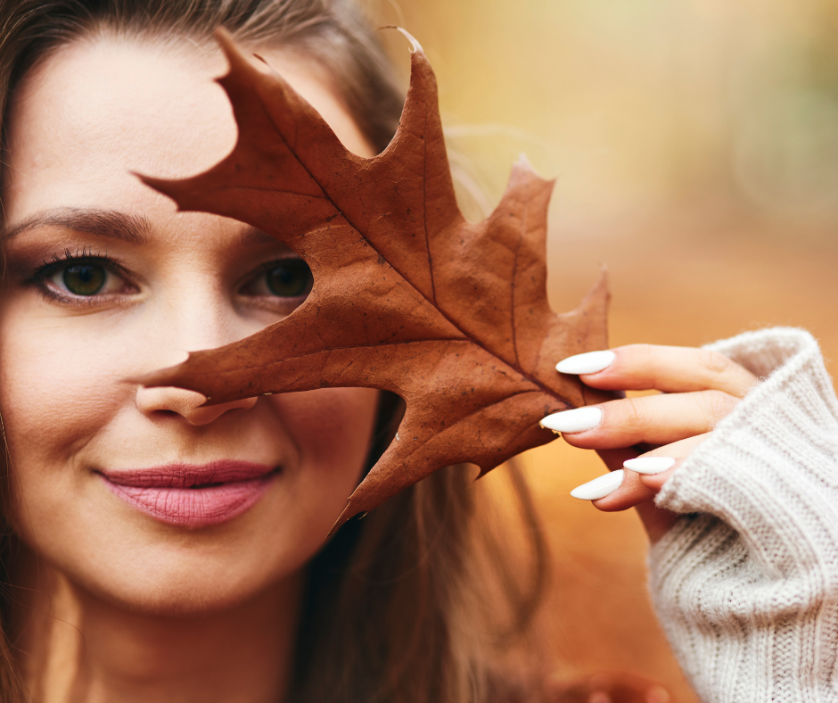 face-hebst-fall Gesicht einer Frau, herbstliches Portrait. Die Frau hält einen Herbstblatt vor dem Gesicht.